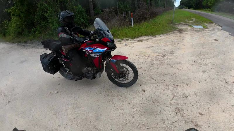 Riding buddy on a red adventure bike crossing a sandy patch